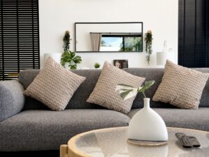 Grey sofa with textured cushions and a round coffee table with a white vase.