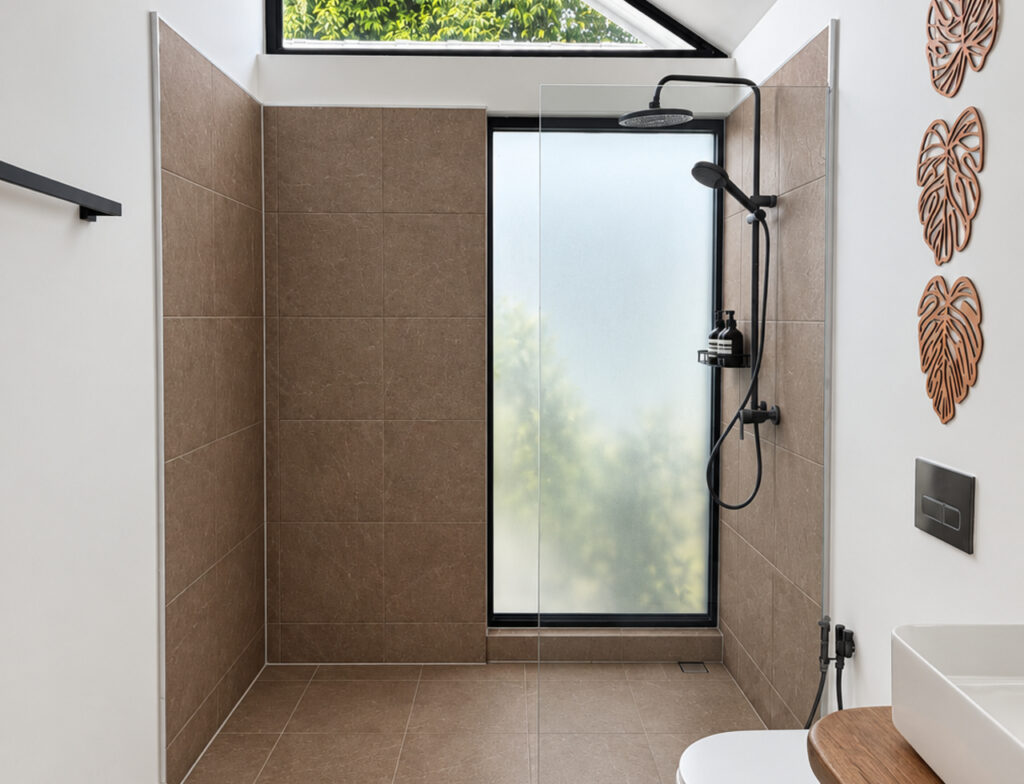 Walk-in shower with black fixtures and a tall frosted window.