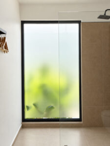 Shower area with an overhead showerhead and a tall frosted window.