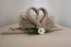 Two folded towel swans and flowers arranged on the bed.