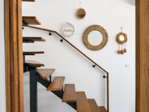 Wooden staircase and round woven mirrors on the white wall.