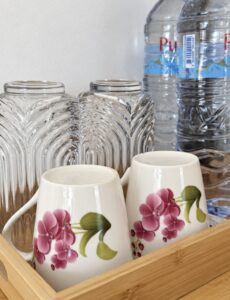 Floral cups, glasses and bottled drinking water on the refreshment tray.