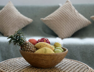 Wooden fruit bowl on a woven coffee table in front of the sofa.