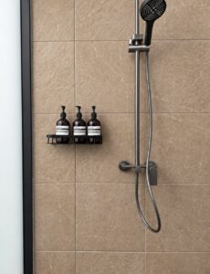 Handheld shower and three toiletry dispensers on the tiled wall.