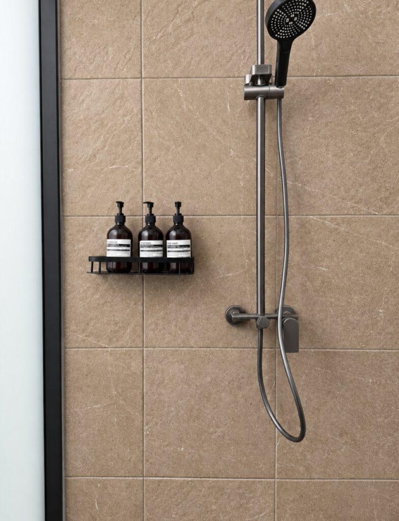Handheld shower and three toiletry dispensers on the tiled wall.