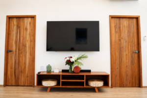 Television and low wooden media unit between two wooden doors.