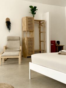 Wooden wardrobe and cushioned armchair beside the bed.