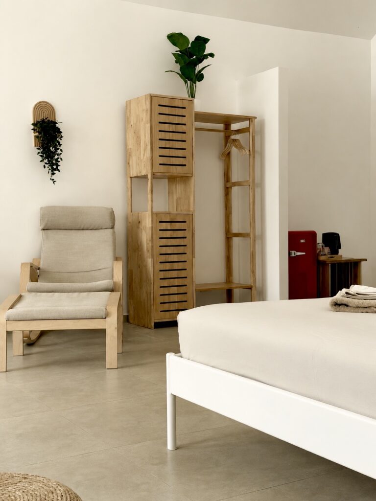 Wooden wardrobe and cushioned armchair beside the bed.
