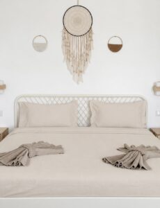 Bed pillows and folded towels beneath the woven wall hanging.