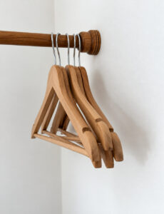 Wooden clothes hangers on the open wardrobe rail.