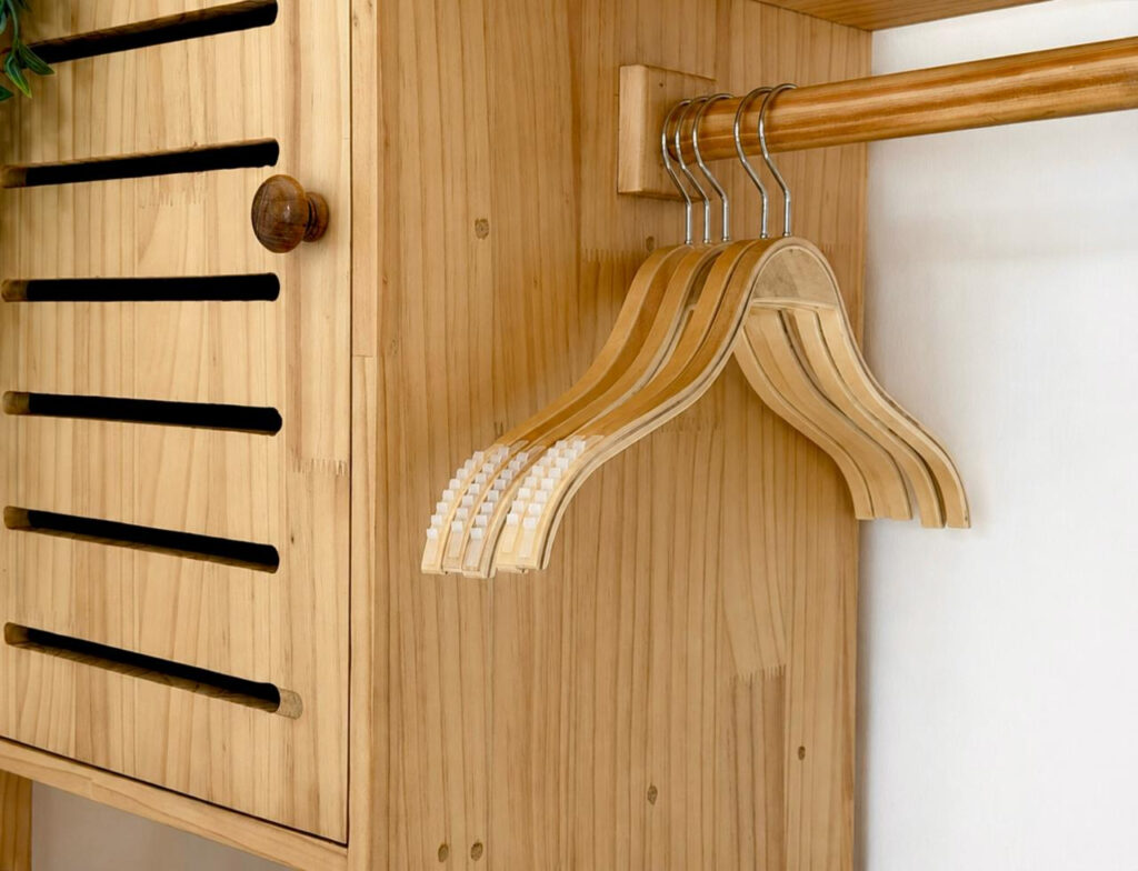 Wooden clothes hangers on an open wardrobe rail.