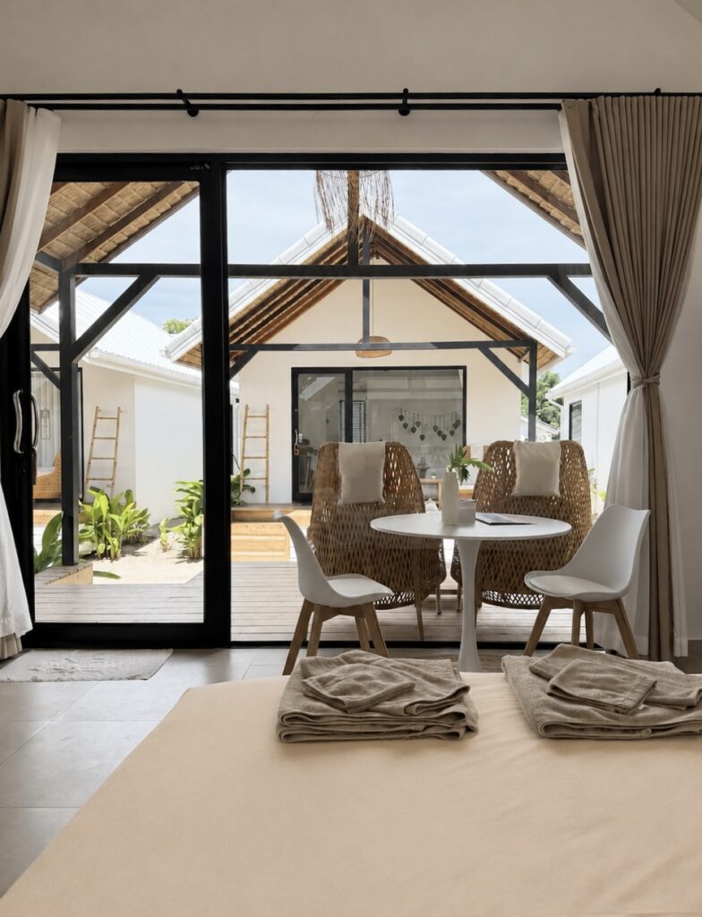 View across the bed towards the dining table and glass doors to the terrace.