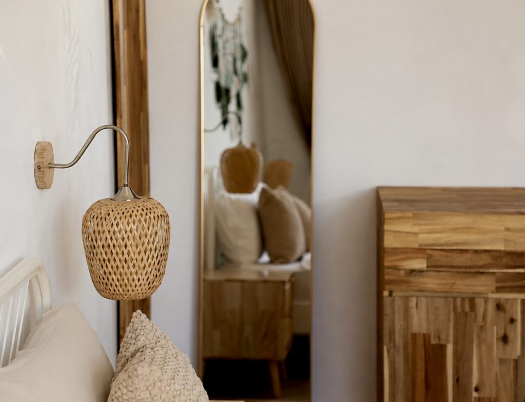 Woven bedside light, bed pillows and wooden wardrobe details.