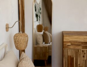Woven bedside light, bed pillows and wooden wardrobe details.
