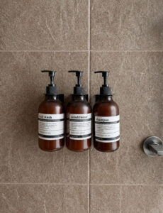 Three wall-mounted toiletry dispensers against the shower wall.