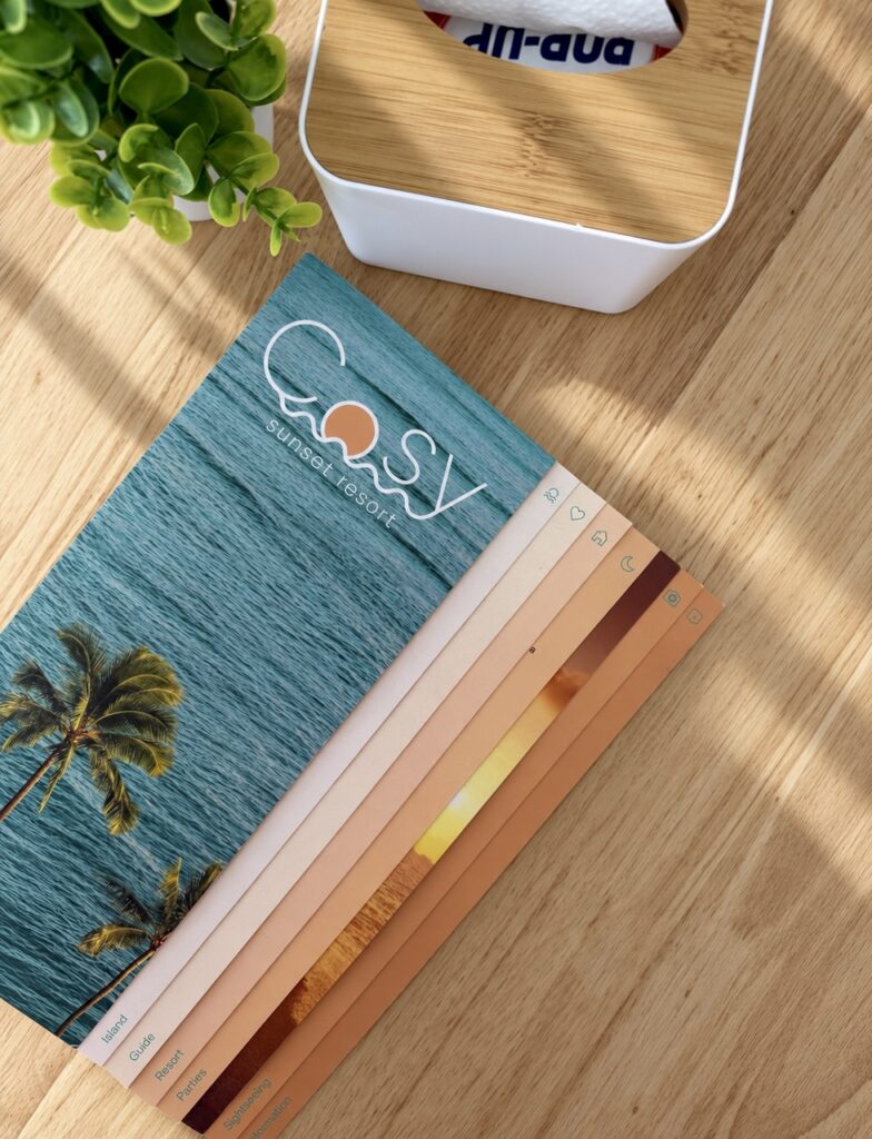 COSY booklet, tissue box and a small plant on the wooden tabletop.
