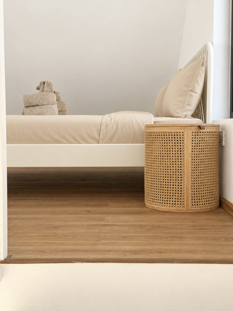 Side view of the bed and a small woven bedside table.