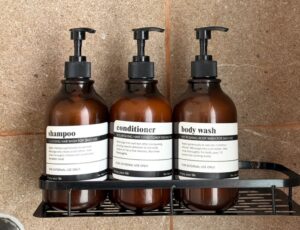 Three toiletry dispensers mounted on the shower wall.